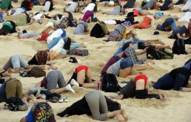 Photo publiée par le site 350.org le 13 novembre 2014 montrant des Australiens la tête dans le sable sur une célèbre plage de Sydney pour alerter le Premier ministre australien Tony Abbott des dangers du changement climatique - Tim Cole